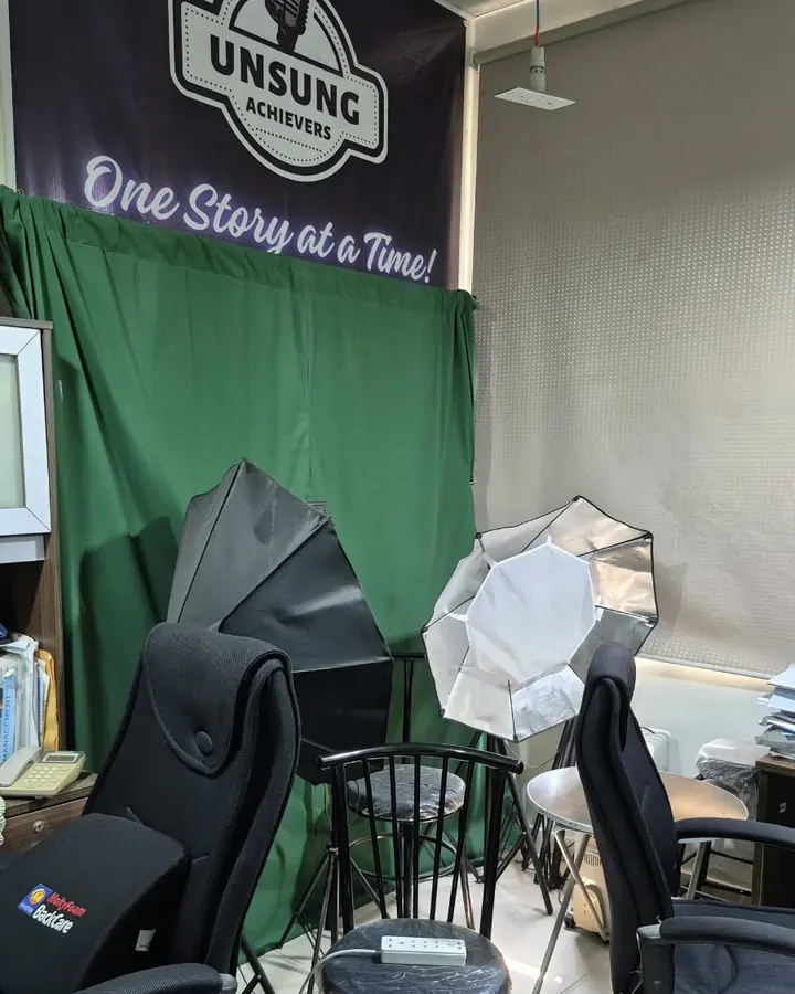 The Unsung Achievers studio: a chair, lights and the banner One Story at a Time